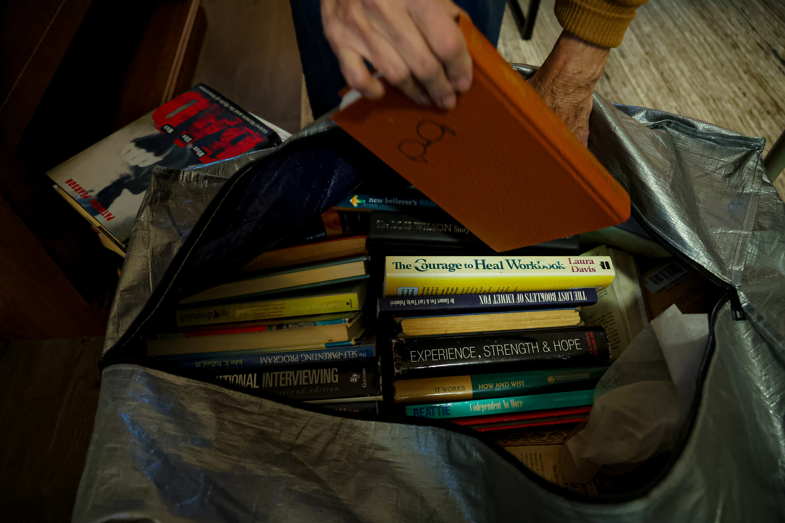 Pamela Hemphill unpacks a variety of self-help books at her apartment in Boise, Idaho, on June 17, 2024. Hemphill served two months in prison for her actions at the Jan. 6, 2021, insurrection at the Capitol and has since become an outspoken critic of former President Donald Trump. (Photo by Donovan Johnson/News21)