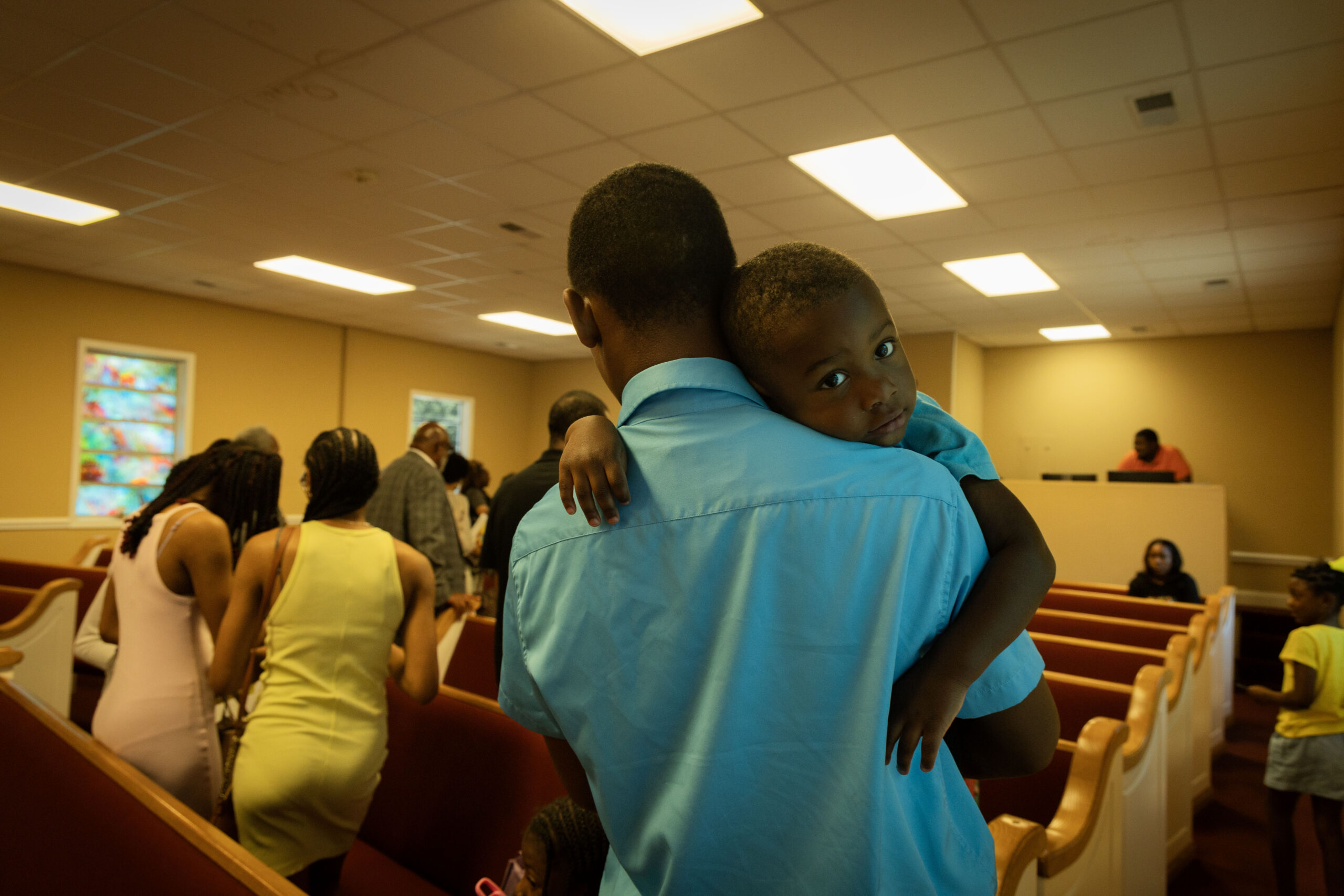 Zy Beasley leans on the shoulder of his father after Sunday service at Holly Grove Baptist Church in Jemison,Ala., on June 16, 2024. (Photo by Jordan Moore/News21)